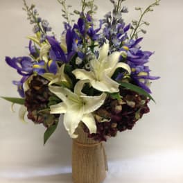 Bouquet of white lilies and purple irises in a burlap-wrapped vase