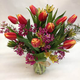Bouquet of red tulips and purple filler flowers in a glass vase
