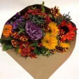 Mixed bouquet with purple, yellow, orange, and red flowers in brown paper
