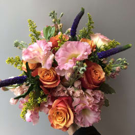 Handheld bouquet of pink and orange roses with purple spikes