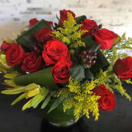 Bouquet of red roses with yellow filler in a glass vase