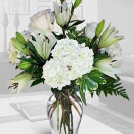 White lilies and hydrangeas in a clear glass vase