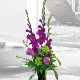 Tall purple floral arrangement in a rectangular glass vase