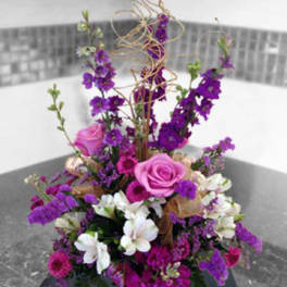 Tall purple and pink floral arrangement with white blooms in a vase