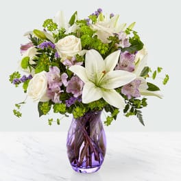 White lilies and roses in a purple glass vase