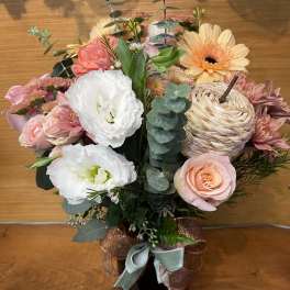 Pink and white mixed flower arrangement in a black vase with ribbon
