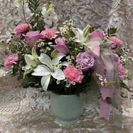 Pink and white floral arrangement in a pale green vase with a ribbon bow