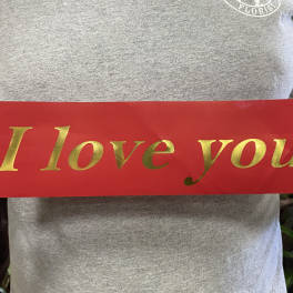 Person holding a red sign that says "I love you" in gold letters