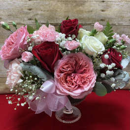 Pink and red rose bouquet in a clear glass vase with baby's breath