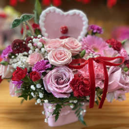 Pink rose bouquet with red carnations and a heart topper in a pink box