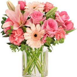 Pink and peach lilies, roses, gerberas, and carnations in a clear glass vase