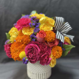 Bright mixed bouquet in a white vase with a striped ribbon