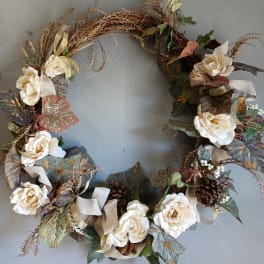 Floral wreath with cream roses and mixed foliage on a gray wall
