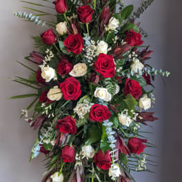 Tall standing spray of red and white roses with greenery
