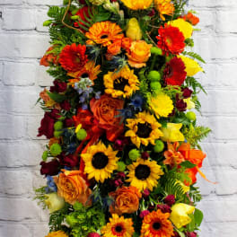 Tall arrangement of sunflowers, roses, and gerbera daisies in bright mixed colors