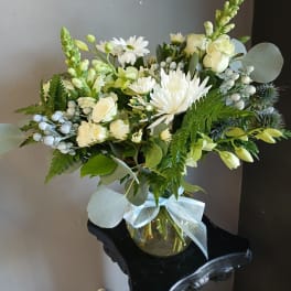 White floral bouquet in a glass vase with a pale ribbon