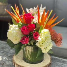 Bouquet of pink roses, white hydrangeas, and orange tropical blooms in a glass vase
