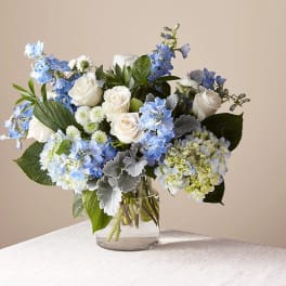 Blue and white bouquet of roses and hydrangeas in a glass vase