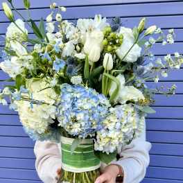 Large bouquet of white and blue flowers in a glass vase