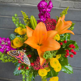 Bouquet of orange lilies, yellow mums, and purple flowers with a butterfly accent