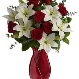 Red roses and white lilies in a red glass vase