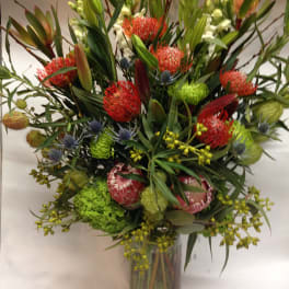 Tall mixed bouquet in a glass vase with red and green blooms