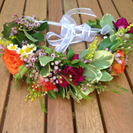 Floral crown with orange and pink roses and a white ribbon tie