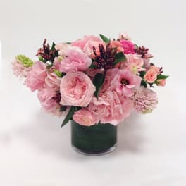 Pink mixed flower arrangement in a dark glass vase