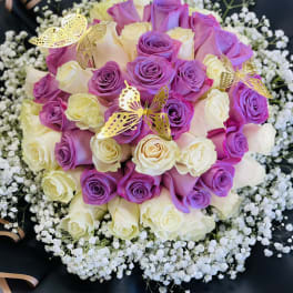 Bouquet of purple and cream roses with baby’s breath and gold butterfly picks