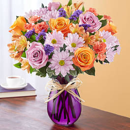 Mixed bouquet of roses, daisies, and alstroemeria in a purple vase