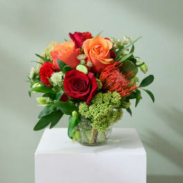 Bouquet of red and orange roses in a clear glass vase
