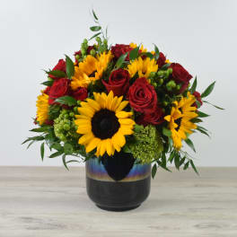 Bouquet of red roses and yellow sunflowers in a dark vase