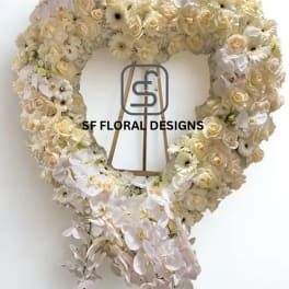 Large heart-shaped standing wreath of ivory roses, gerbera daisies, and orchids on a wooden easel