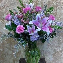 Pink roses and lavender lilies in a glass vase