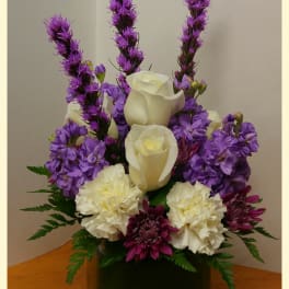 Purple and white floral arrangement in a dark vase