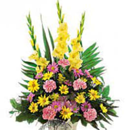 Tall mixed floral arrangement in a square vase with yellow and pink blooms