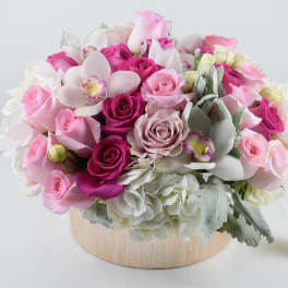 Pink and white rose arrangement in a round wooden container