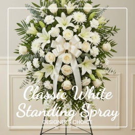 White standing spray with lilies, roses, and a ribbon on an easel