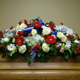 Large floral casket spray with red, white, and blue flowers