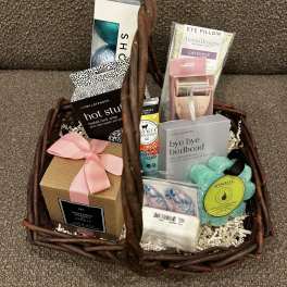 Basket of assorted spa and bath gift items with a pink ribbon