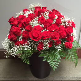 Red roses arranged in a black vase with white baby's breath