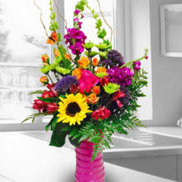 Bright mixed bouquet in a pink vase with a sunflower and orchids