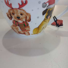 White mug with holiday dog illustrations and a red Santa hat