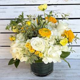 White and yellow flower arrangement in a dark glass vase