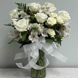 White rose bouquet in a glass vase with a sheer ribbon bow