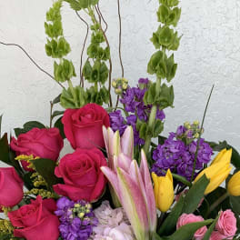 Mixed bouquet with hot pink roses, purple blooms, and yellow tulips