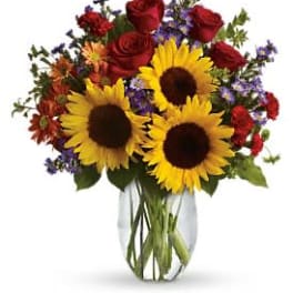 Bouquet of sunflowers and red roses in a clear glass vase