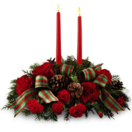 Christmas centerpiece with red candles, red flowers, pinecones, and striped ribbon