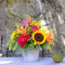Mixed bouquet in a white pot with sunflower, roses, gerbera daisies, and lilies