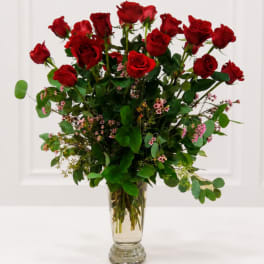 Tall bouquet of red roses in a clear glass vase